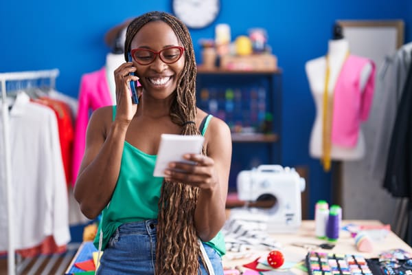 Photo d'une jeune commerçante africaine qui montre son smartphone avec une boutique en ligne ouverte, ambiance lumineuse et moderne